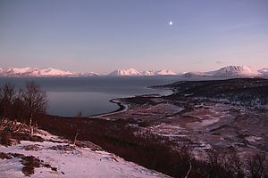 An early afternoon view over Karlsøy with the moon in the sky.