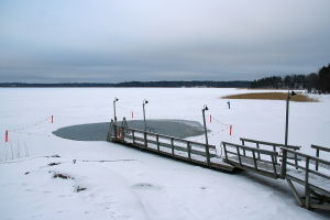 Ice swimming place and a lonely skier on the Laajalahti bay, Helsinki, Finland.