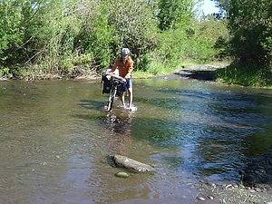 Arto crossing a river on a small gravel road.